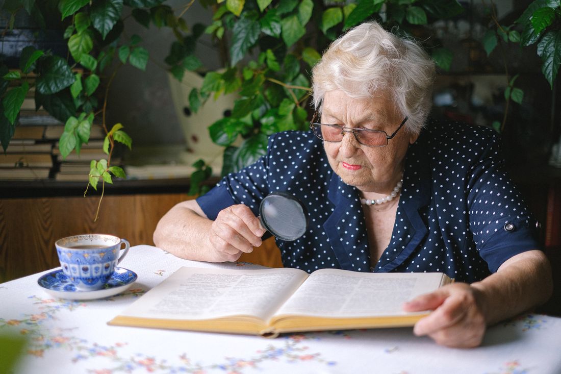Older woman reading with a magnifier. Illustrative stock photograph